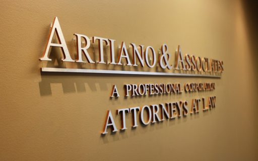 metal faced acrylic letters in brushed aluminum on orange acrylic mounted with stud mounts inside lobby wall