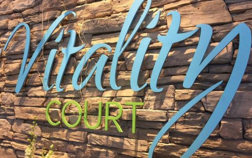 custom painted solid cut aluminum letters mounted on stone inside lobby in bright blue and lime green