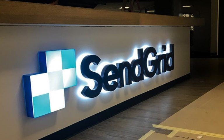 Backlit logo sign on indoor lobby reception desk - sendgrid