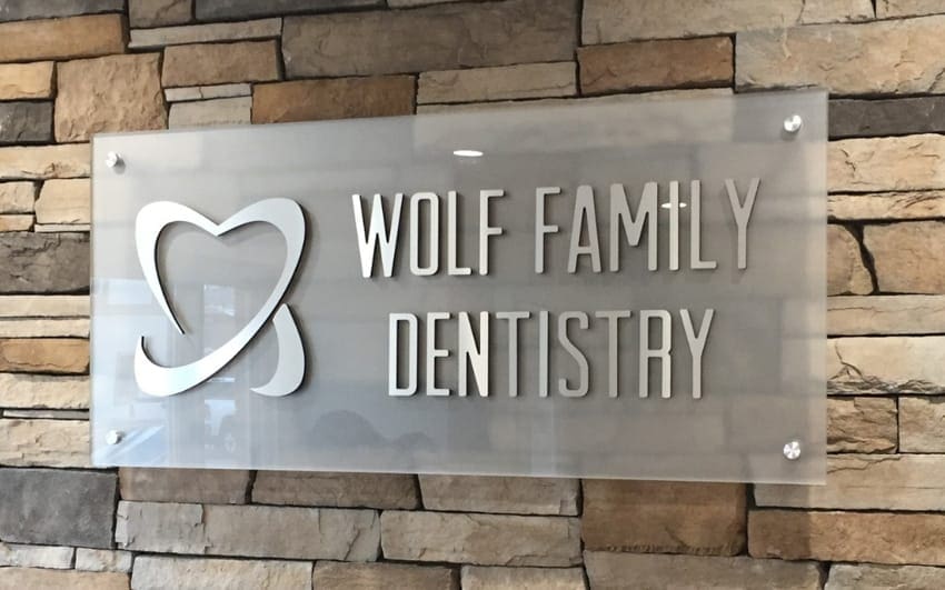 Frosted acrylic and metal logo panel sign — Wolf Dentistry reception