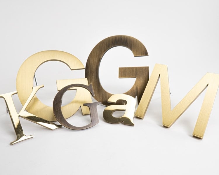 Grouping of solid brass sign letters in multiple finishes