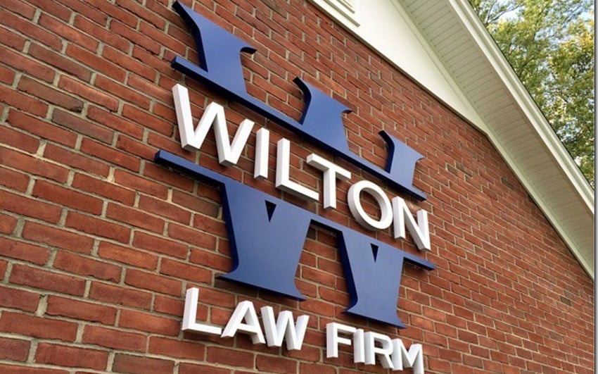 Fabricated matte-painted metal letters spelling Wilton Law Firm mounted on a brick exterior wall