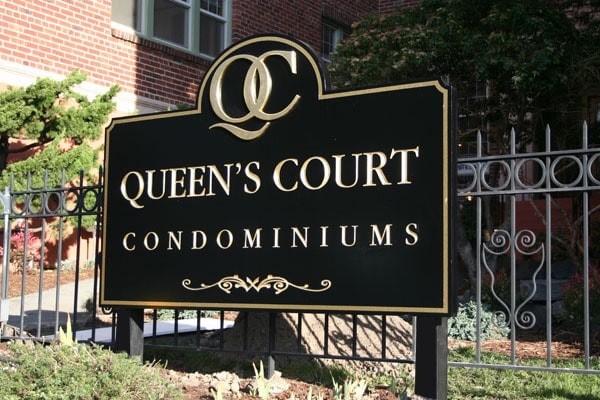 Carved HDU monument sign with painted gold lettering, post-mounted at Queens Court