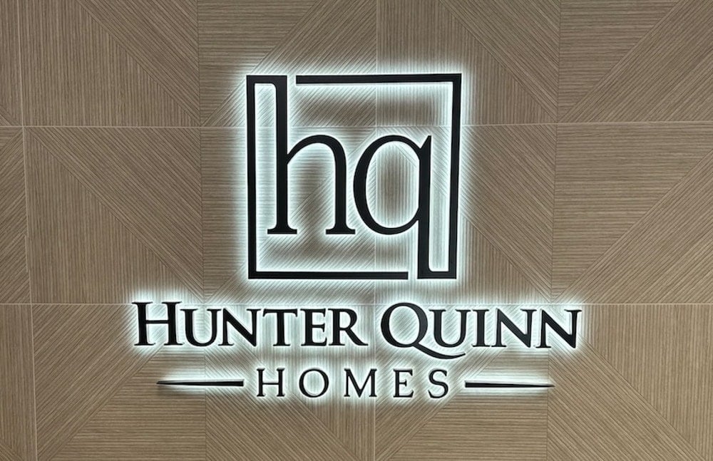 Backlit metal logo sign in a corporate office lobby — Hunter Quinn Homes